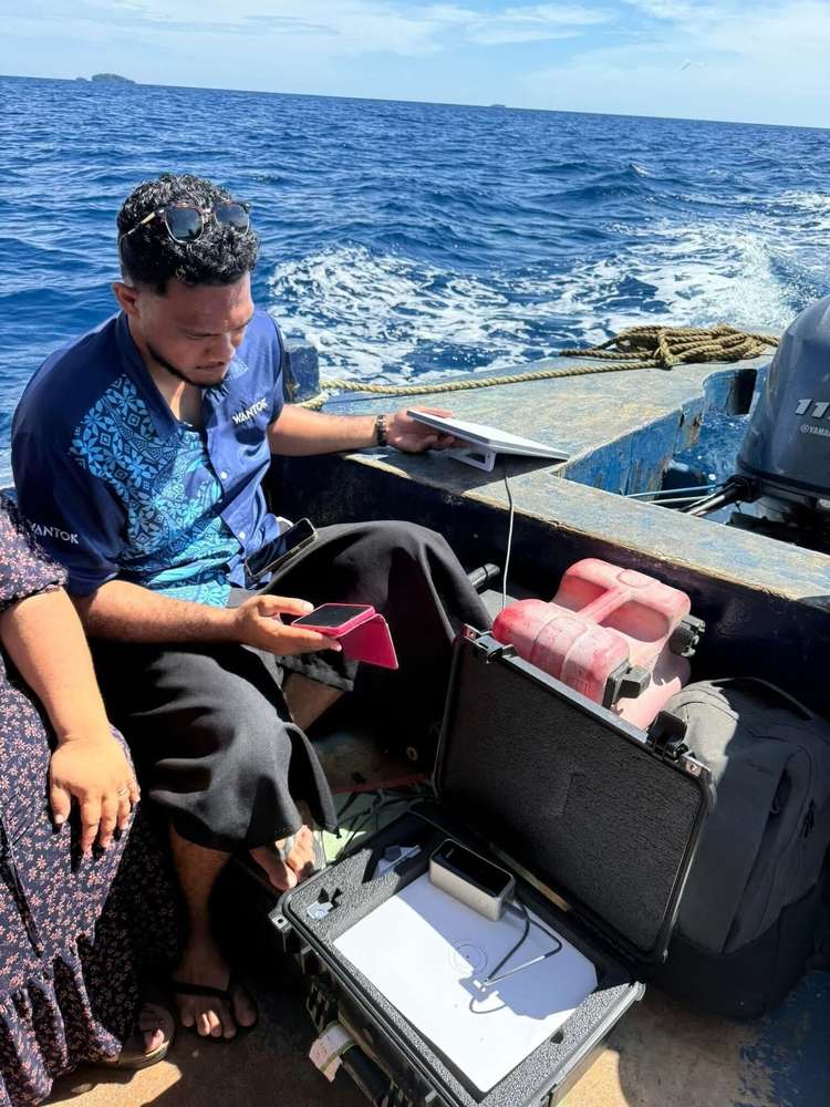A WanTok technician setting up a Starlink dish aboard a small boat at sea
